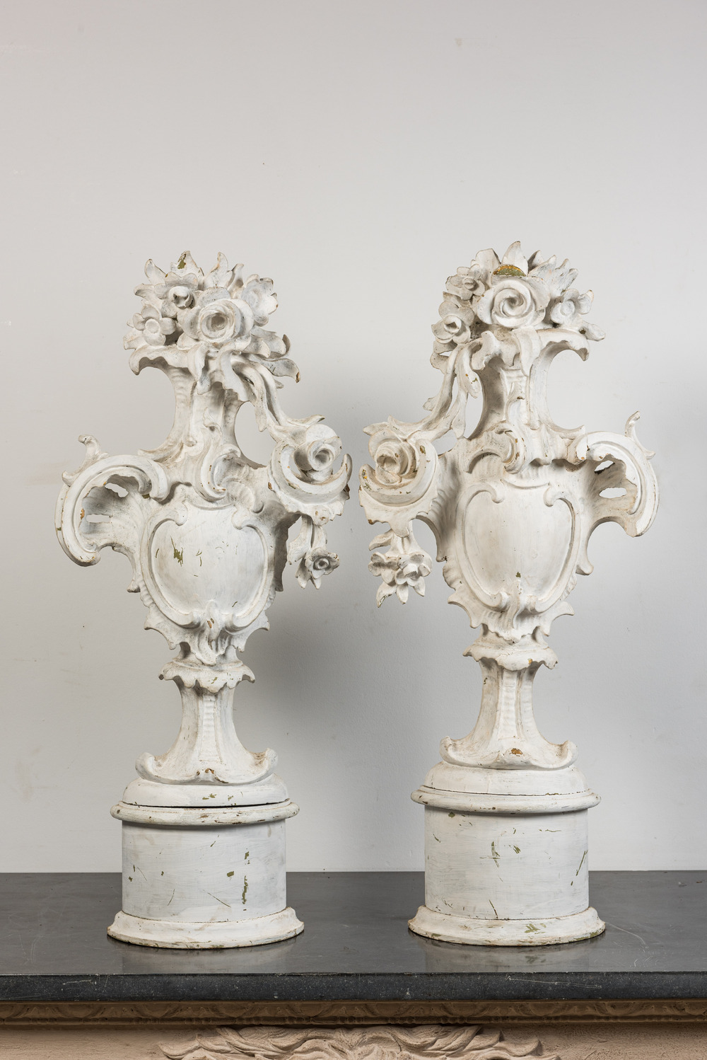 Paire de grands ornements en bois sculpt&eacute; &agrave; patine blanche orn&eacute;s d'un blason entour&eacute; de fleurs, 18&egrave;me