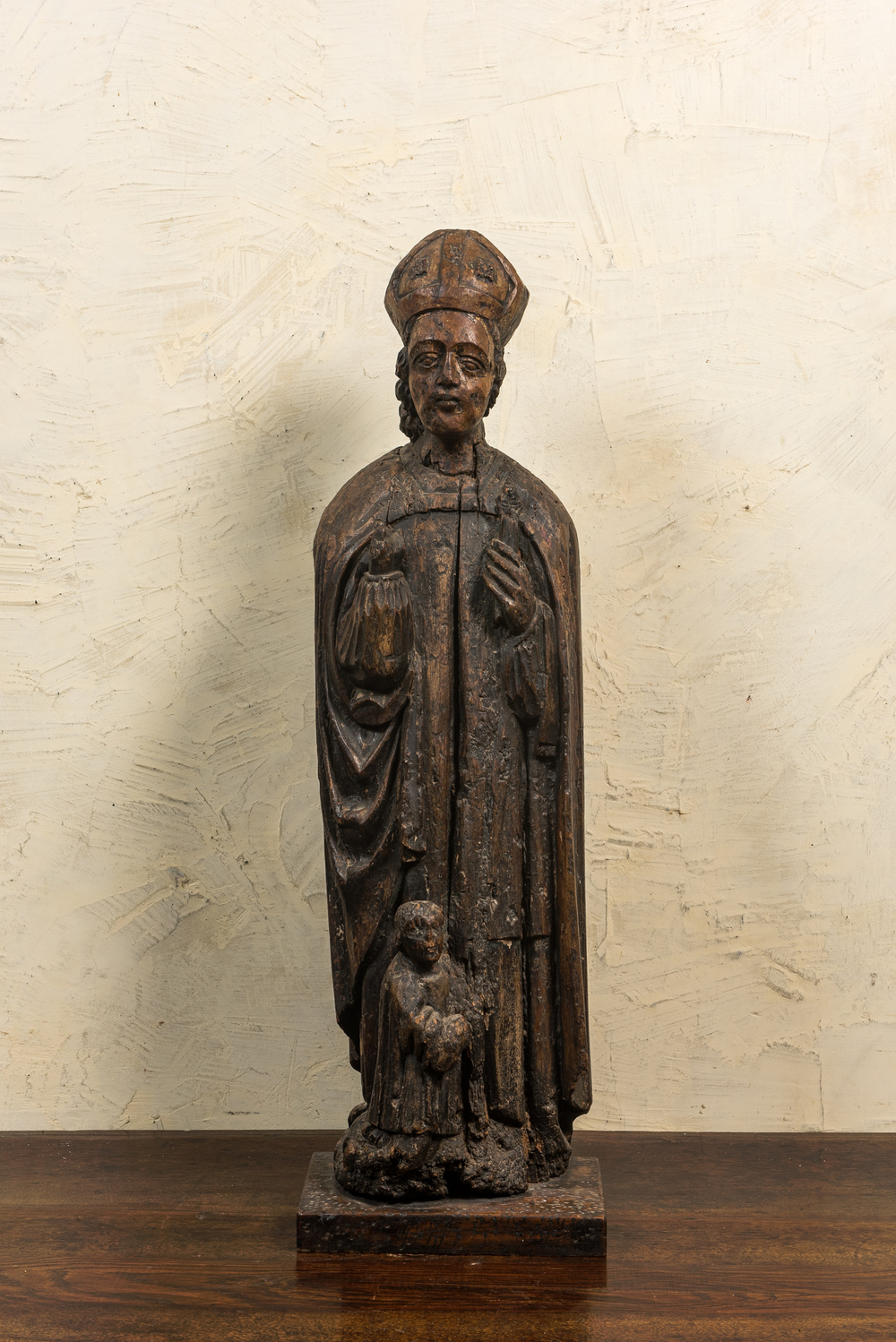 A large wooden sculpture of Saint Nicolas with a kneeling boy, 17th C.