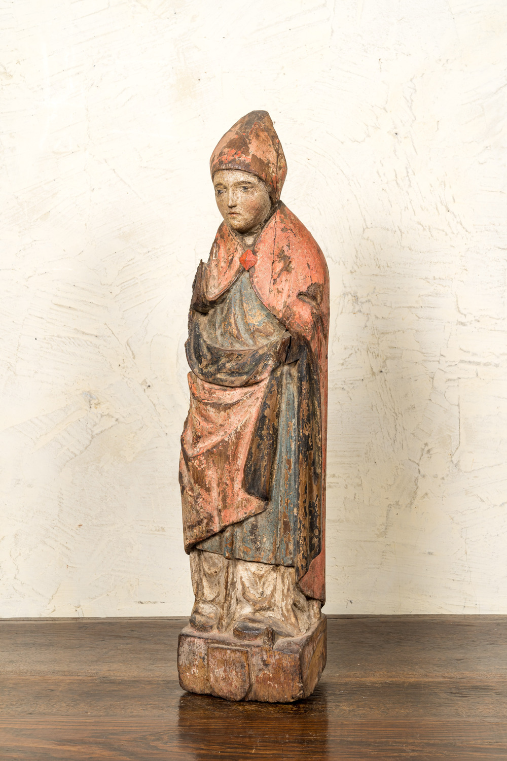 Een Vlaamse polychrome eikenhouten bisschop op een basis met wapenschild, ca. 1500