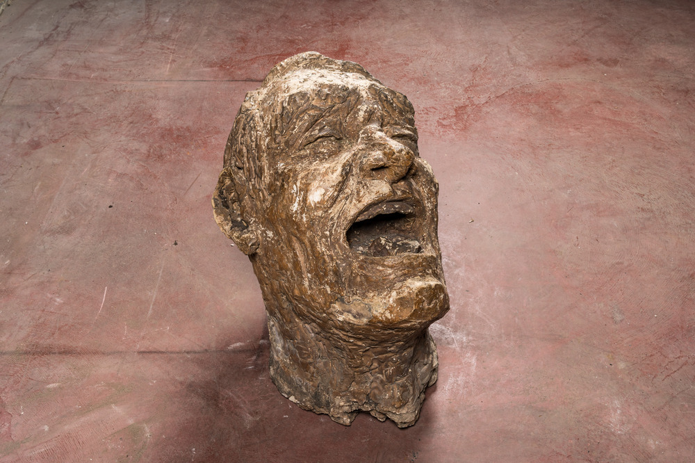Een groot gepatineerd terracotta hoofd van een lachende man, 1e helft 20e eeuw