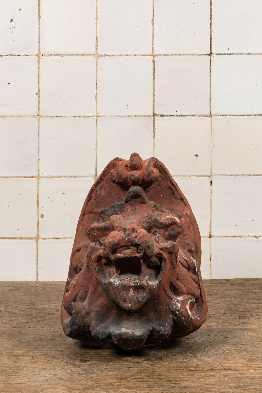 Een gepatineerd terracotta ornament met een leeuwenkop, 19e eeuw