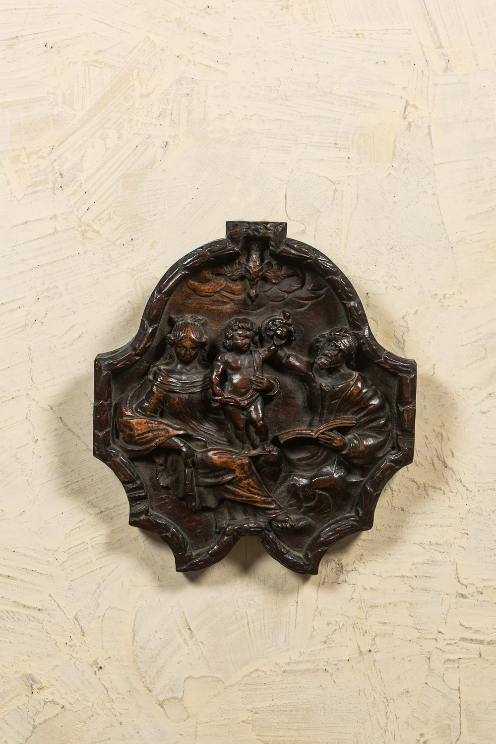 Een notenhouten reli&euml;f met voorstelling van de Heilige Familie en de Heilige Geest, 17/18e eeuw