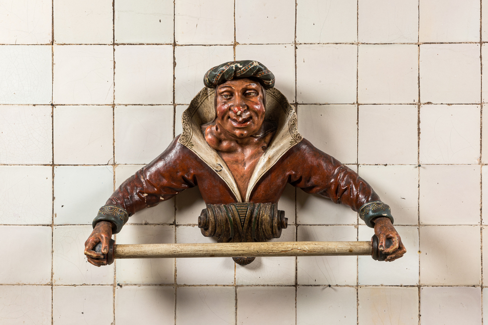 A rare polychromed wooden towel rack in the shape of a mischievous guy, 19th C.