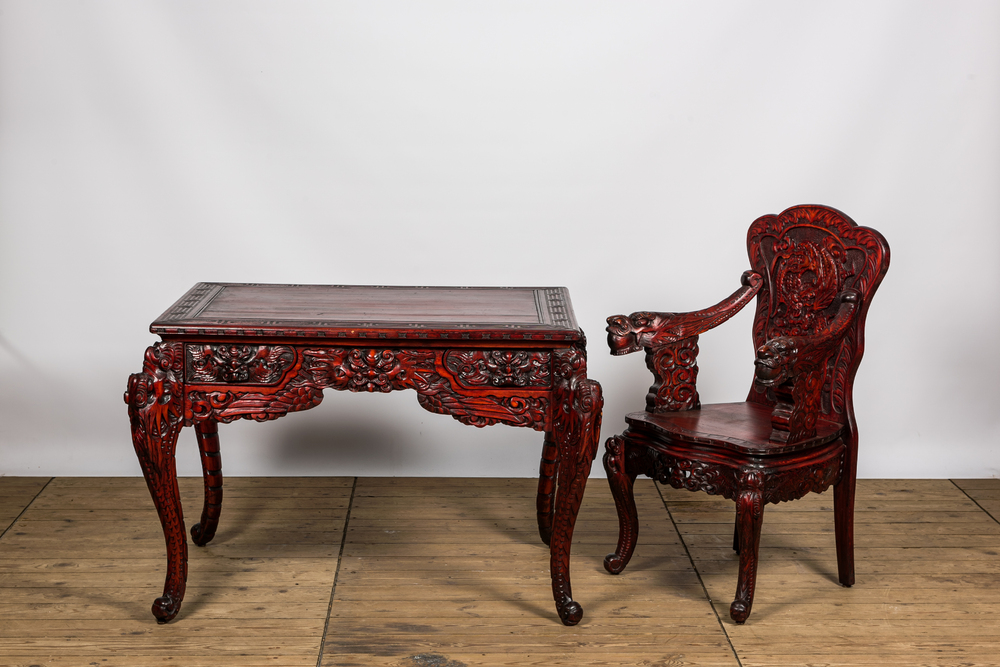 A finely carved Japanese red patinated wooden desk with armchair, 20th C.