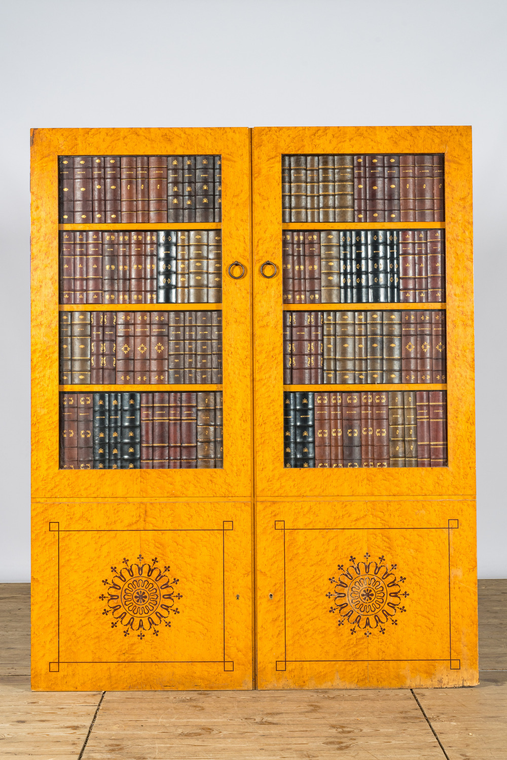 Een Frans esdoorngefineerd 'trompe l'oeil' paneel in de vorm van een bibliotheek, 1e helft 20e eeuw