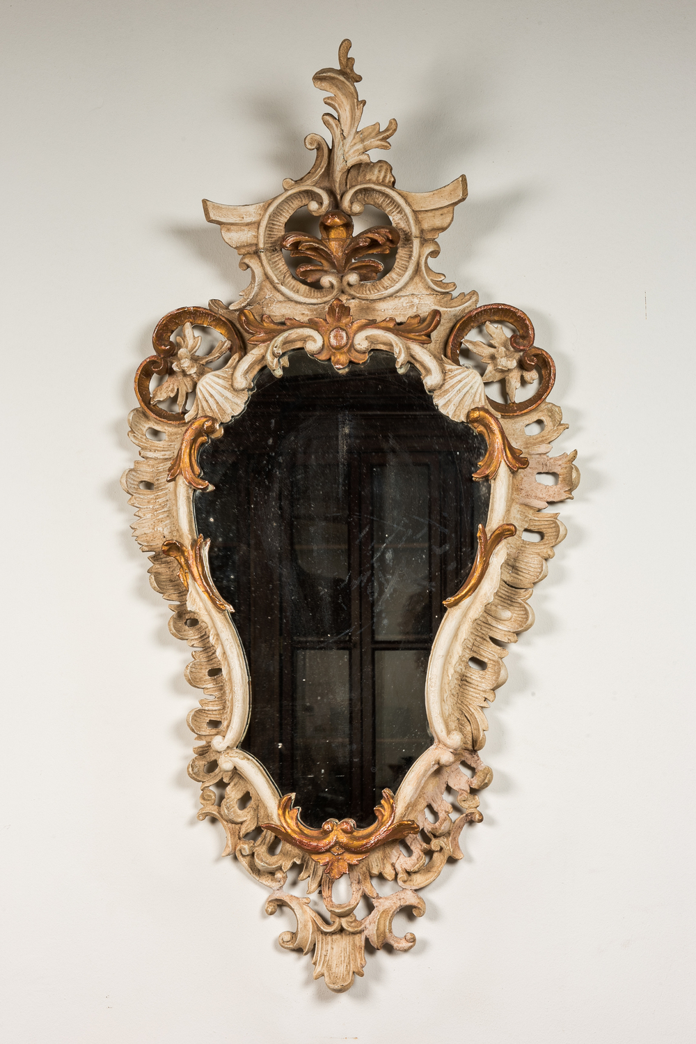 Een Italiaanse gepatineerde en vergulde houten spiegel, 18/19e eeuw