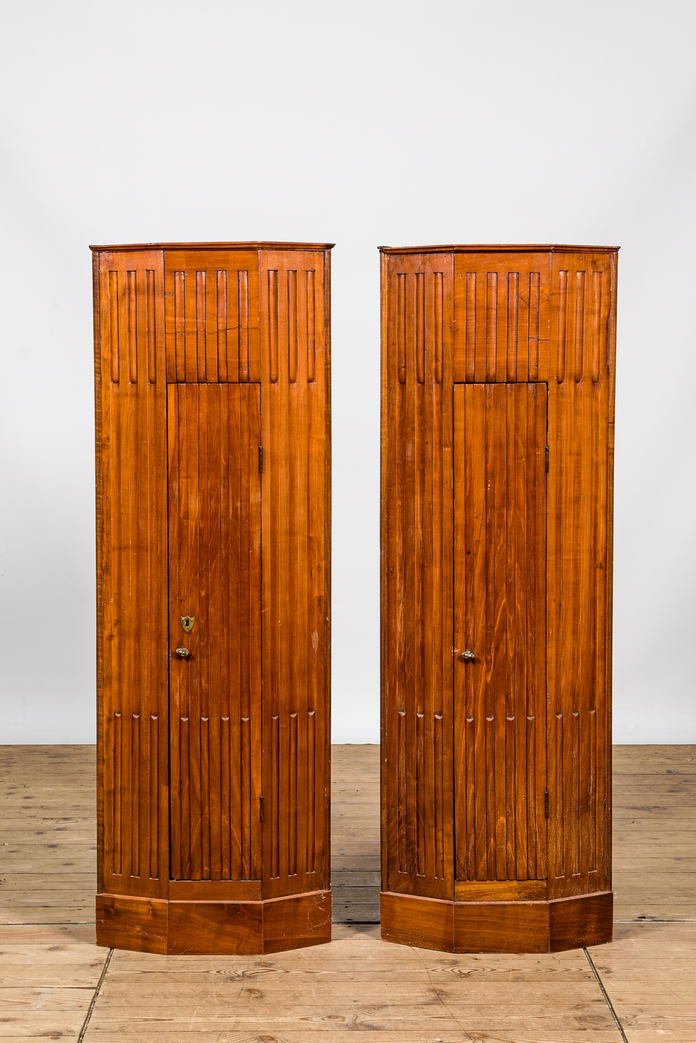 A pair of fluted wooden corner cabinets, 19/20th C.