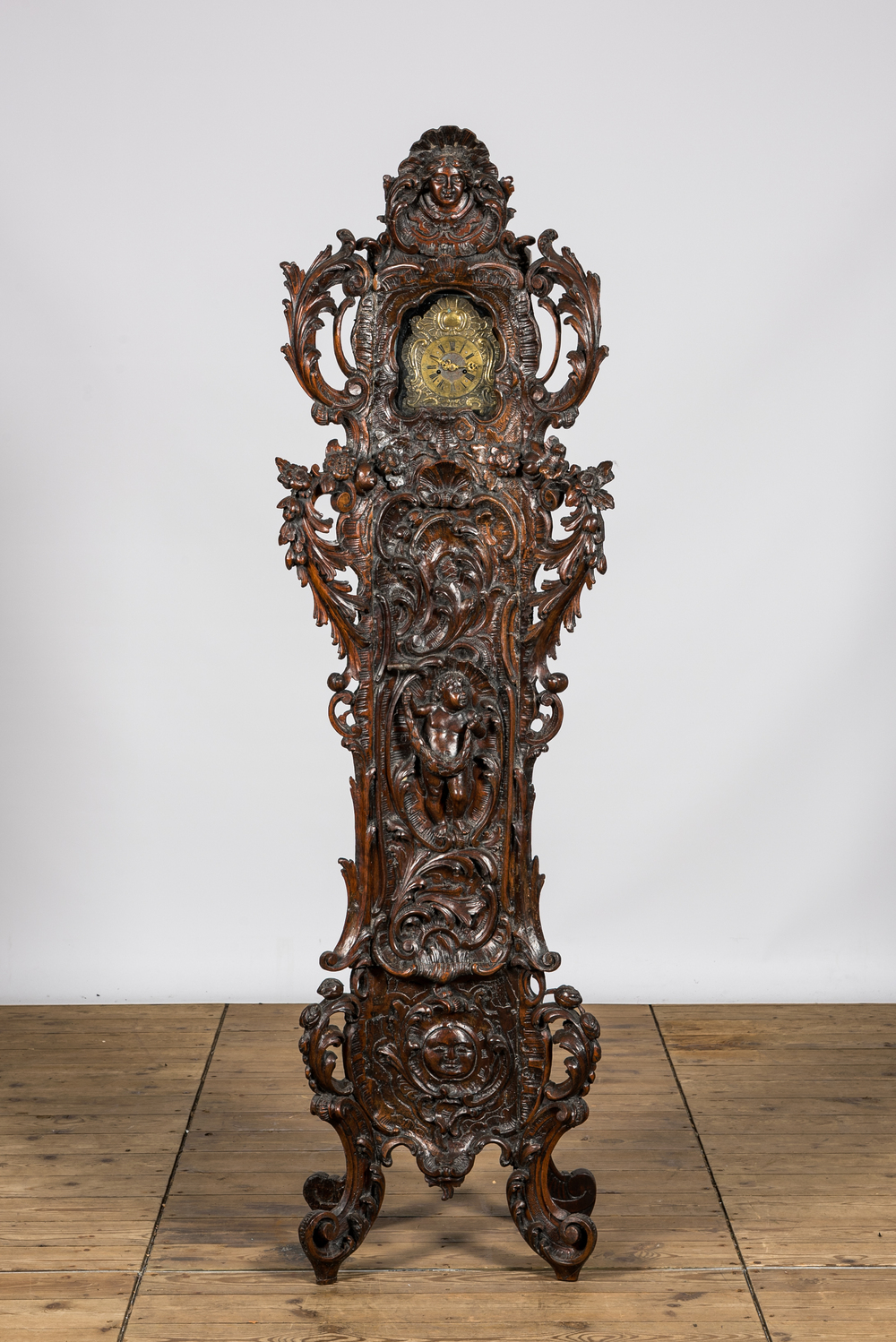 Een rijk gesculpteerde driepotige notelaren staande klok, 19e eeuw