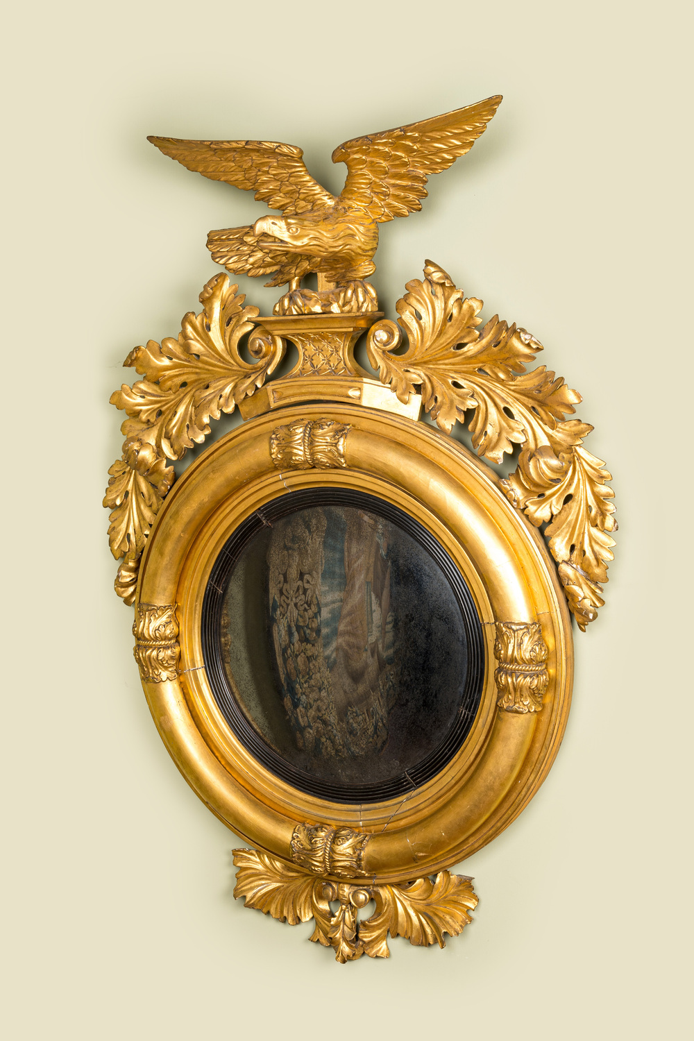 An impressive gilt wooden eagle-topped mirror with ebonised inner medallion, 19th C.