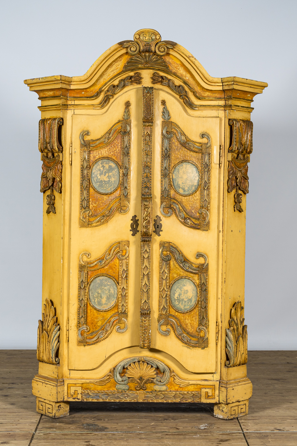 Een Duitse gepatineerde houten tweedeurskast met reli&euml;fdecor en monogram R.K., 19e eeuw
