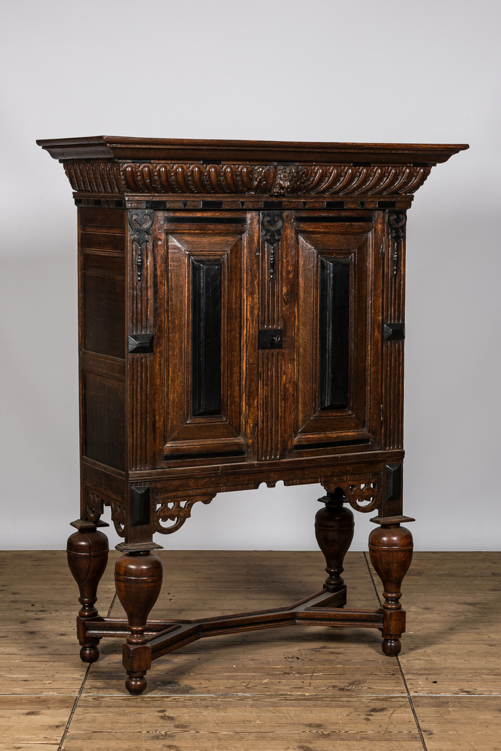 An oak and partly ebonised wooden two-door cupboard on foot, 19th C.