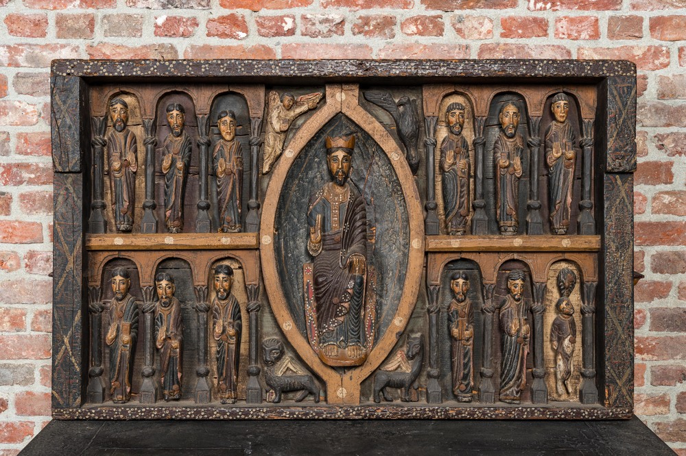 A Spanish polychrome wooden panel depicting Jesus in a medallion surrounded by the twelve apostles after the altar of Sant Pere in Ripoll, 19th C.