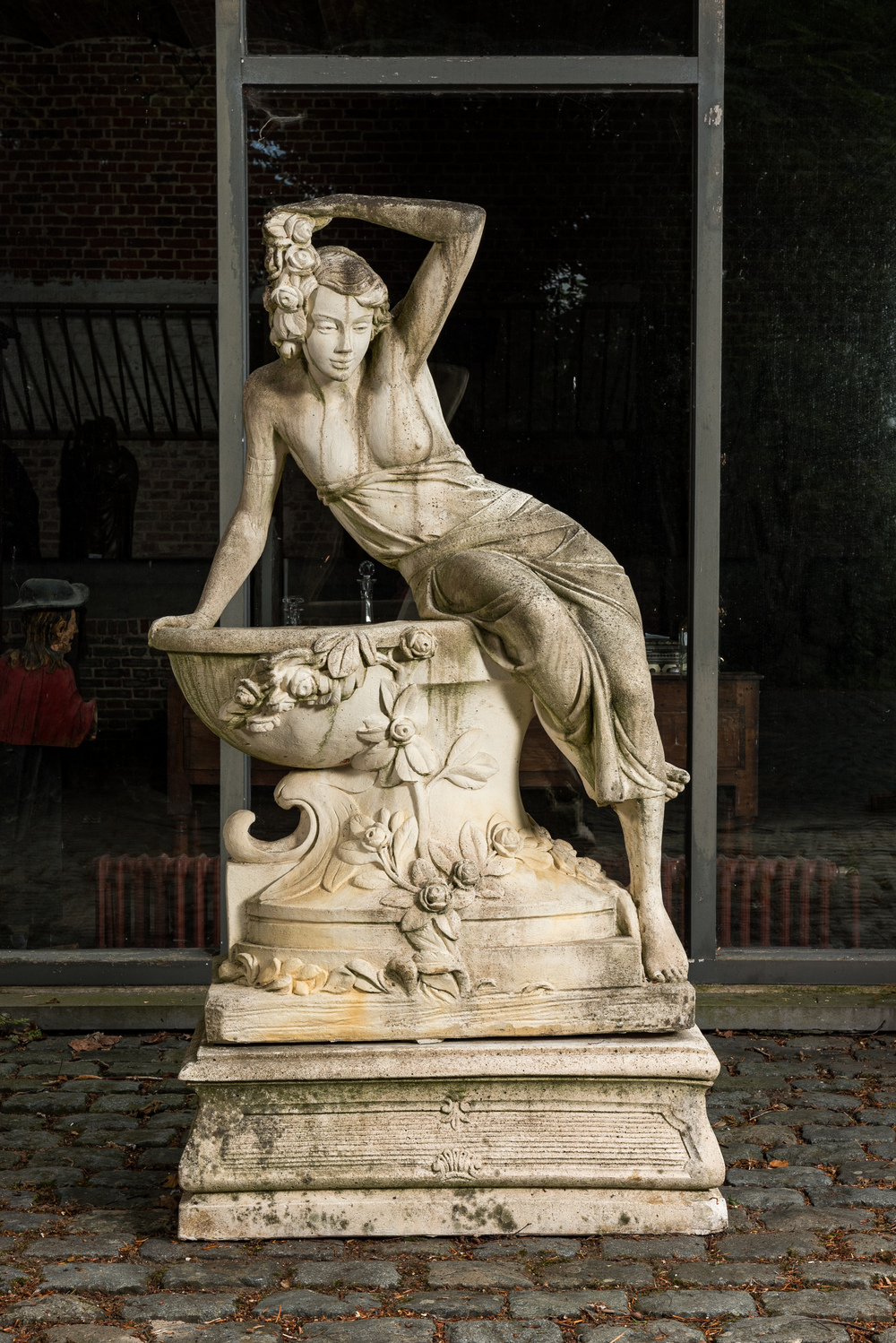 A white painted concrete garden urn flanked by the goddess Flora on matching stand, 20th C.