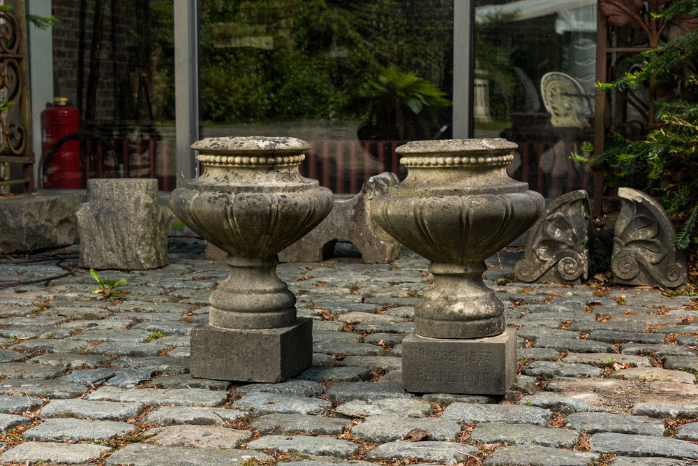 A pair of stone garden vases on square bases, one dated 1873