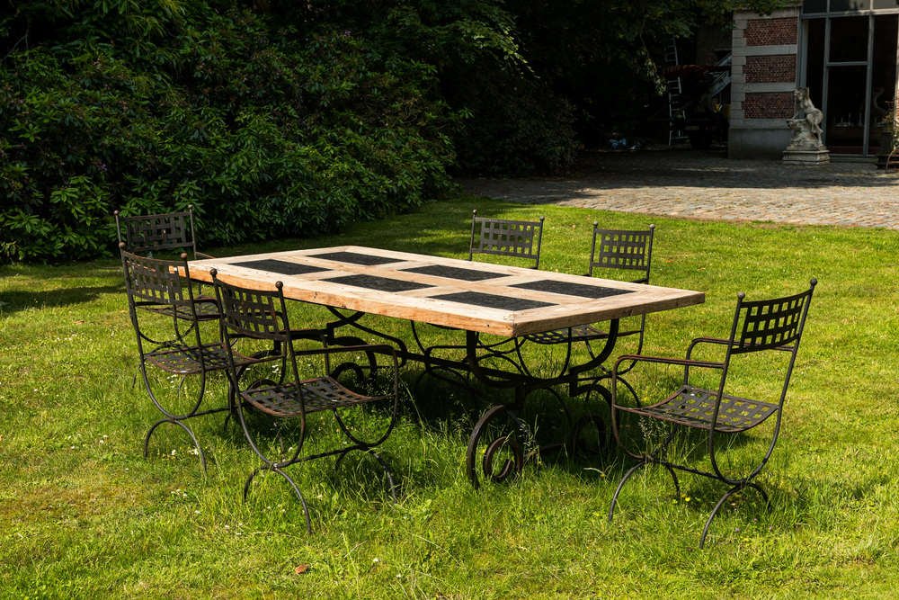 Een smeedijzeren tafel met bovenblad in leisteen en hout en zes stoelen, 20e eeuw