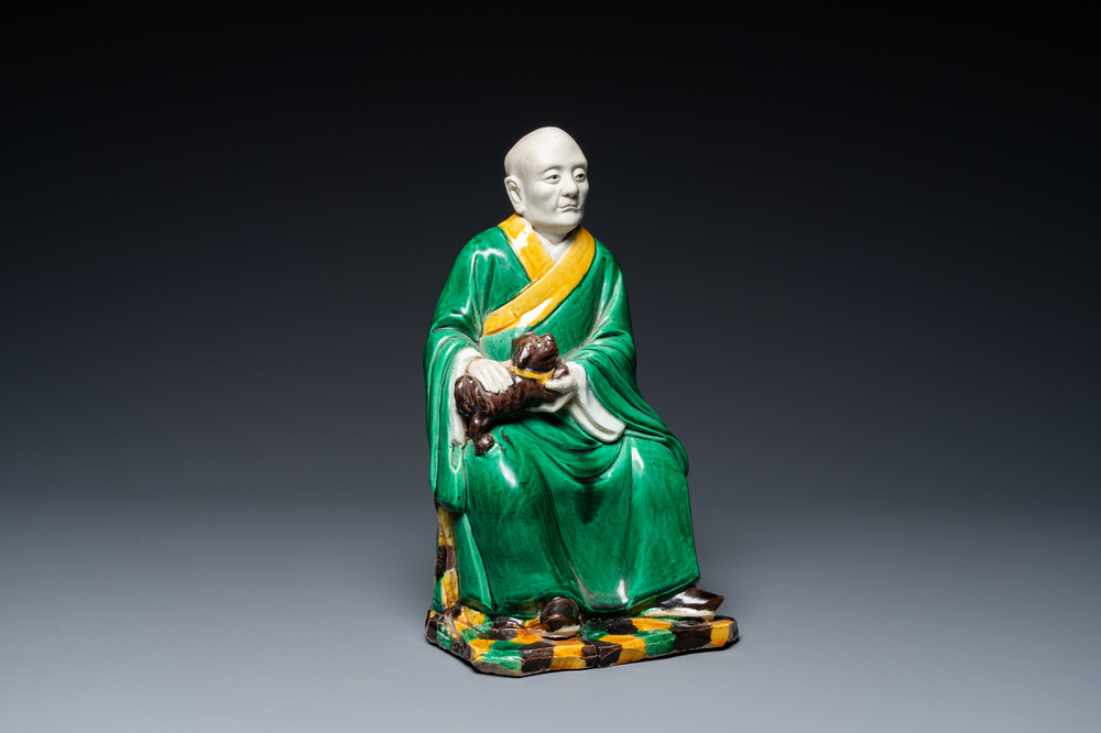 A Chinese verte biscuit figure of a Luohan holding a dog, probably Qing