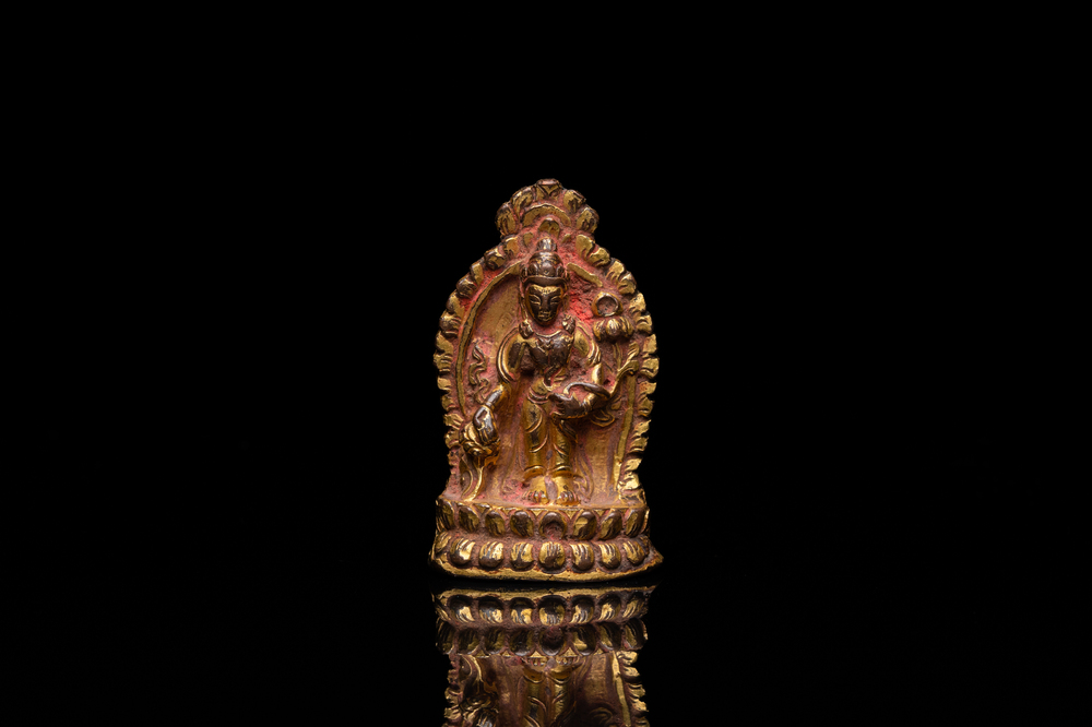 Een vergulde bronzen miniatuur Boeddha met sporen van rode lak, Tibet of Nepal, 15/16 eeuw
