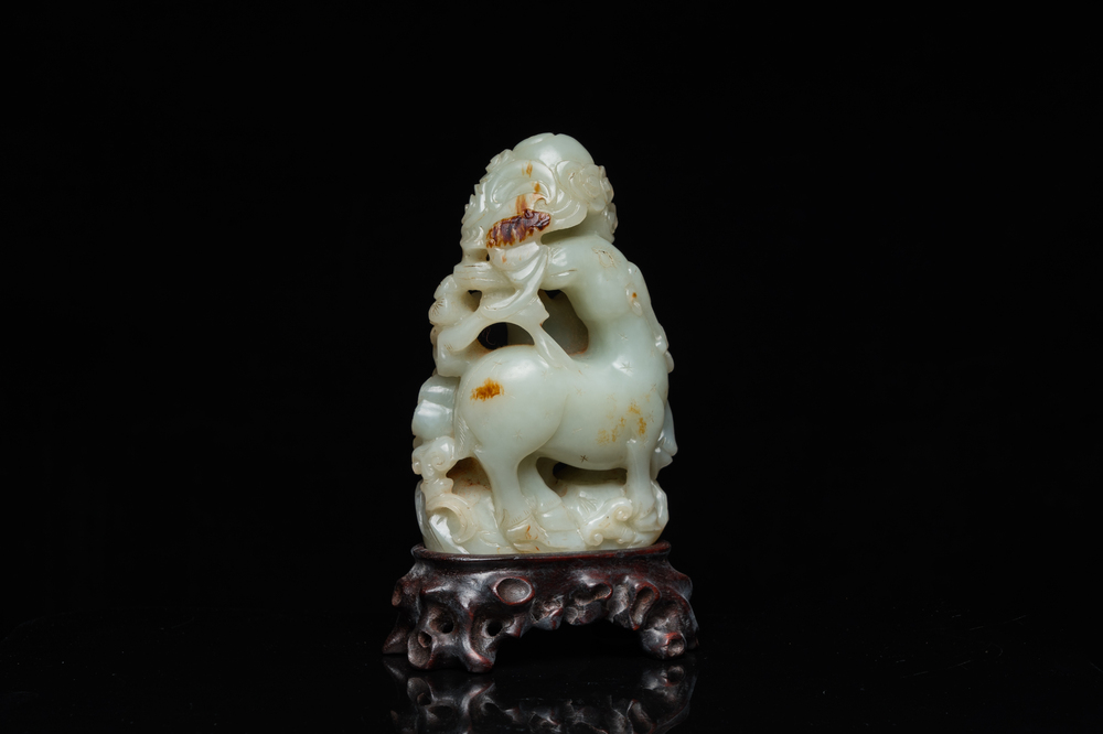 A Chinese celadon and russet jade ram sculpture on wooden stand, 19th C.