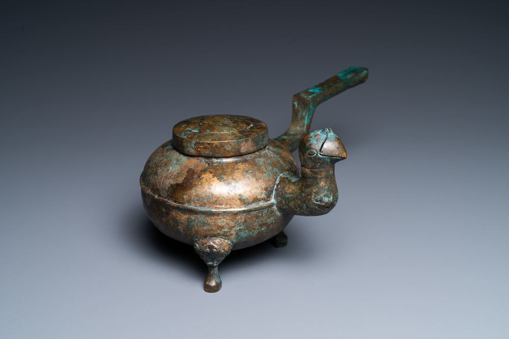 Een Chinese vergulde driepotige bronzen 'he' ketel met een vogelhoofd als tuit, Han