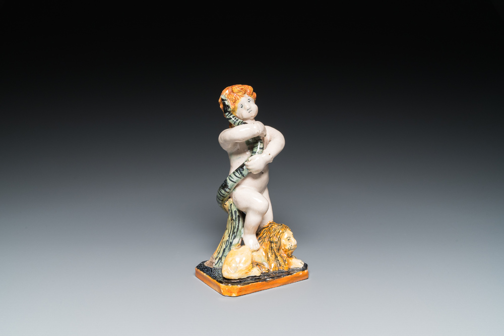 A polychrome Brussels faience sculpture of a putto with a snake standing on a lion, late 18th C.