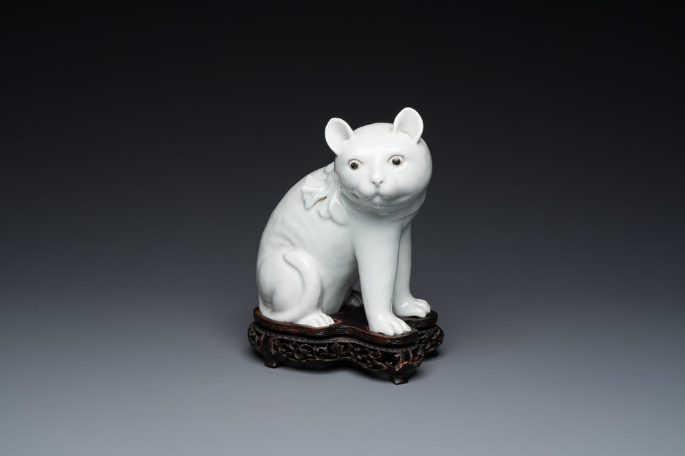 Een Chinees blanc de Chine model van een kat op houten sokkel, Republiek