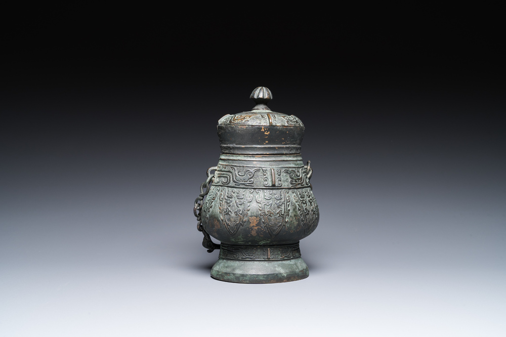 Een Chinese archa&iuml;sche rituele bronzen 'you' wijnkan met deksel in Westelijke Zhou-stijl, Ming
