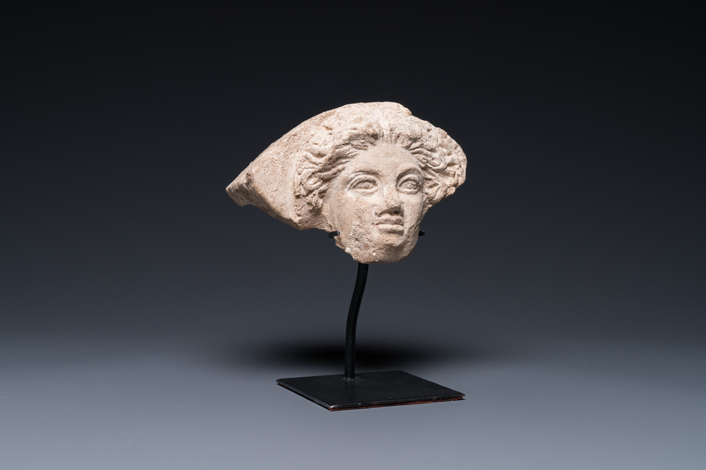 A Greek terracotta with white engobe antefix in the shape of a woman's head, 5/4th C. b.C.