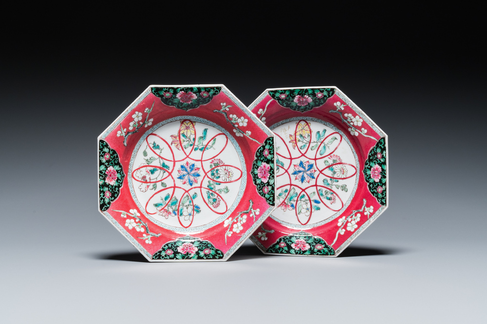 Een paar Chinese octagonale famille rose borden met robijnrode fondkleur, Yongzheng