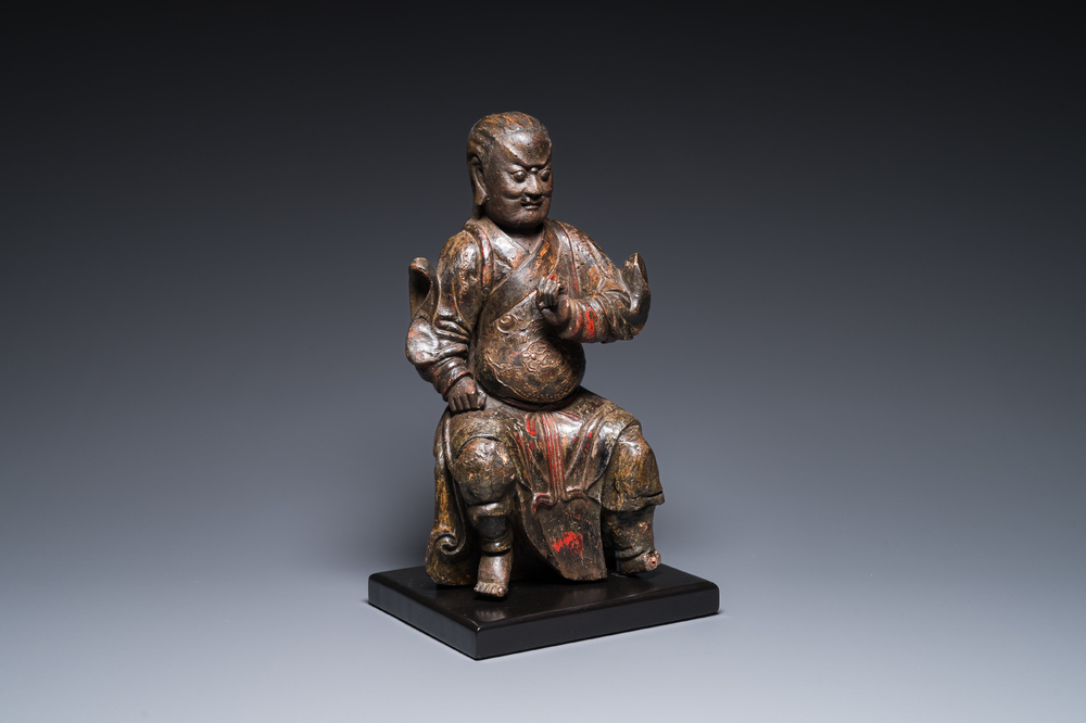 Een Chinese gelakte en gepolychromeerde houten sculptuur van een boeddhistische wachter, Ming