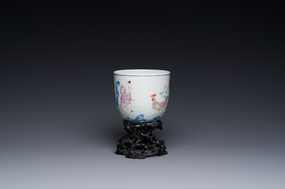 A Chinese famille rose cup with a boy and a rooster on wooden base, Qianlong mark, 20th C.