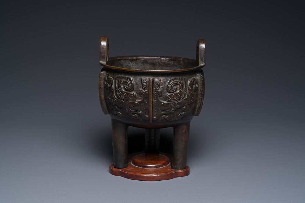 A Chinese archaistic bronze tripod censer on wooden stand, 'ding', Song/Ming