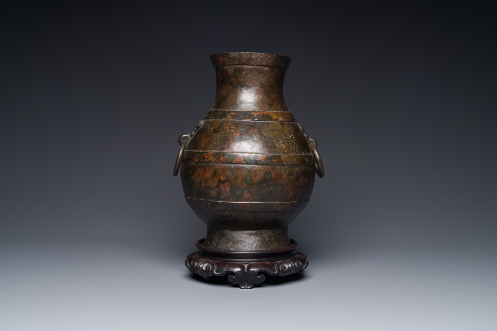 Vase de forme 'hu' en bronze aux anses en forme de taotie dans le style de Han sur socle en bois, Chine, Ming