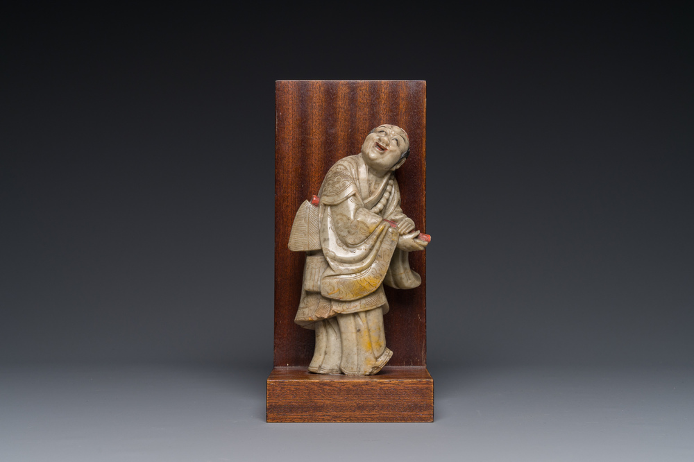 A Chinese partly polychromed soapstone figure on a wooden stand, 18th C.