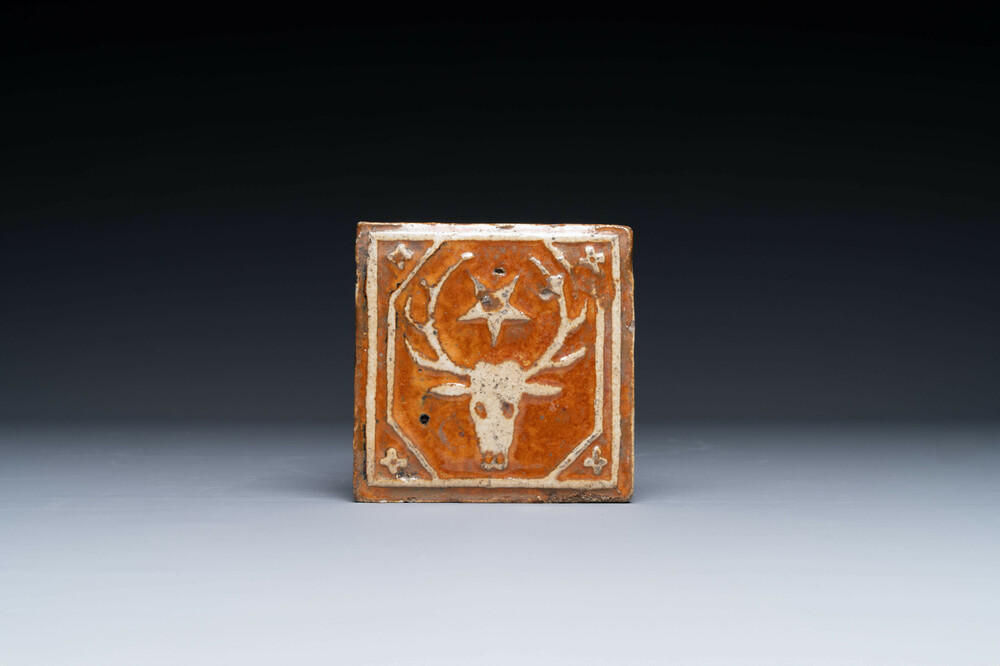 A slip-decorated lead-glazed tile with a stag's head and a star, Flanders or France, 15/16th C.