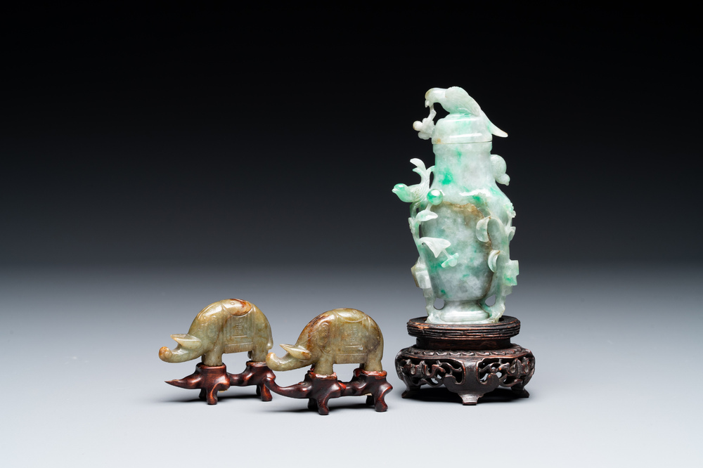 A pair of Chinese jade sculptures of elephants and a covered vase on wooden stands, 19th C.