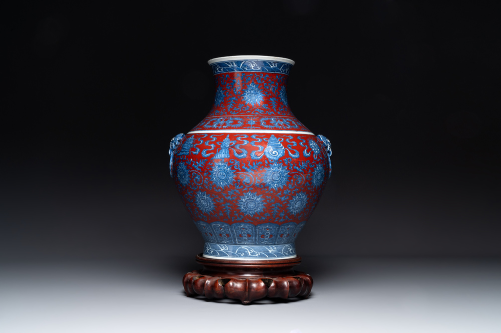 Vase de forme 'hu' en porcelaine de Chine en bleu, blanc et rouge de fer &agrave; d&eacute;cor de 'bajixiang' sur socle en bois, marque de Qianlong, 19&egrave;me