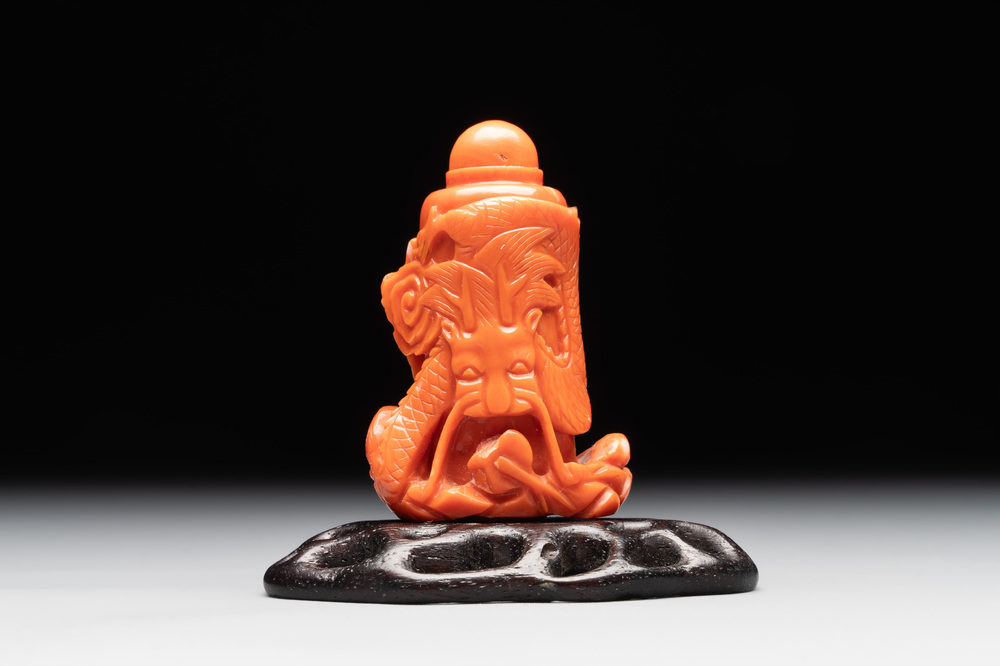 A Chinese carved red coral 'dragon' snuff bottle on wooden stand, 19/20th C.