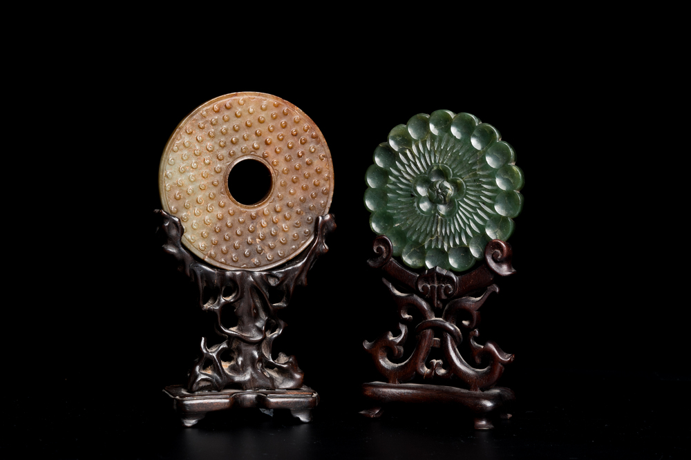 A Chinese russet jade 'bi' disc and a spinach-green flower-shaped pendant on wooden stands, Ming and Qing