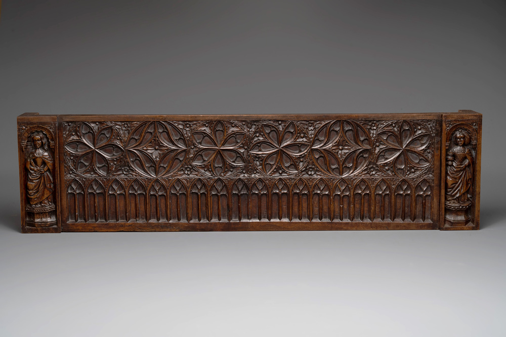 A carved front panel of a Gothic walnut chest with female saints, alcoves and rosettes, France, early 16th C.