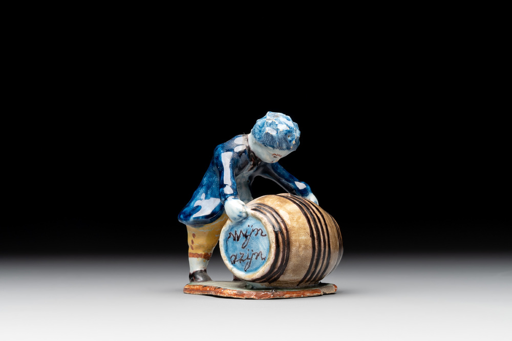 A polychrome Dutch Delft model of a boy rolling a 'wijn azijn' barrel, 18th C.