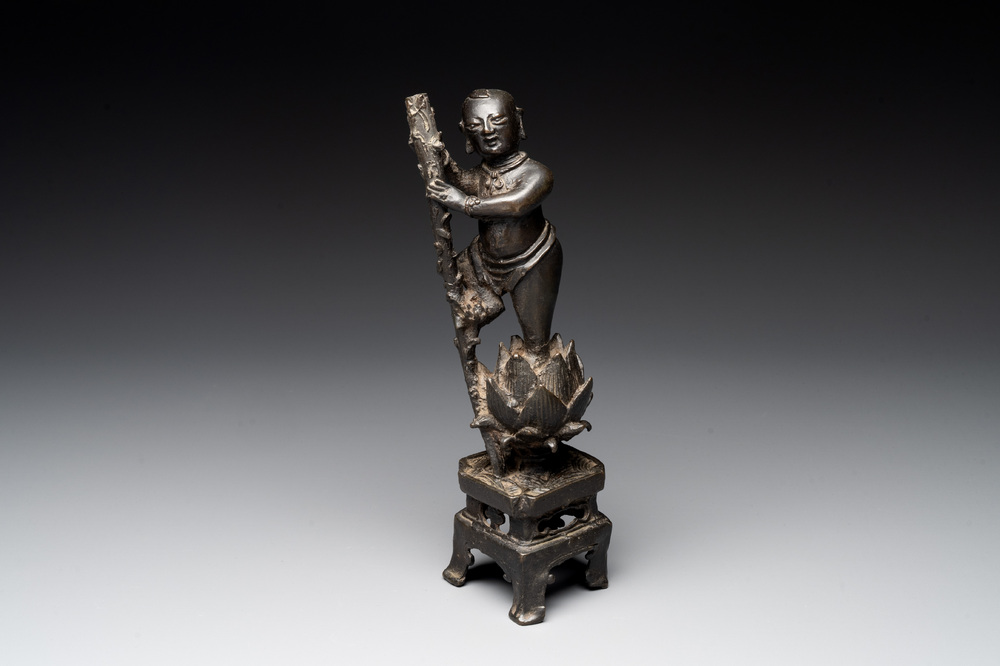 A Chinese bronze incense holder of a boy standing on a lotus, Ming