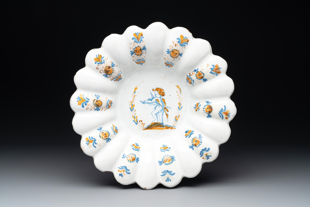 A yellow, blue and white Dutch Delftware dish with a putto playing the violin, Delft or Haarlem, dated 1642