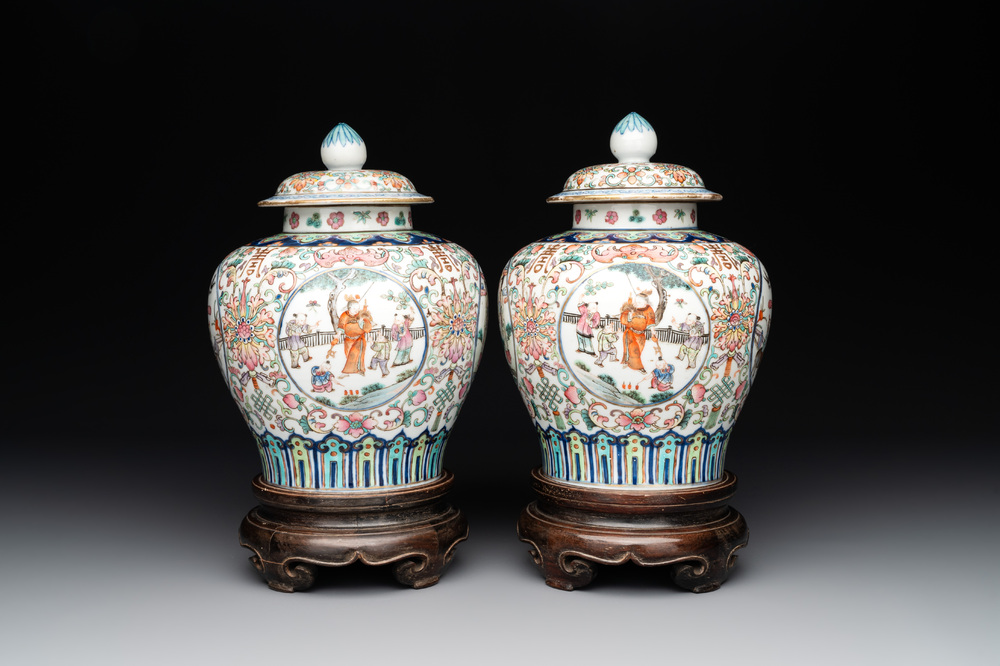 A pair of Chinese famille rose covered vases with figural design and wooden stands, 19th C.