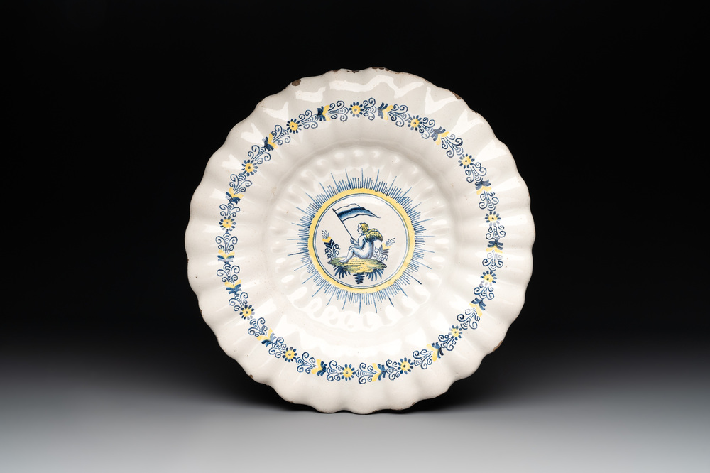 A Dutch Delft or Haarlem blue, white and yellow gadrooned dish with a putto, 17th C.