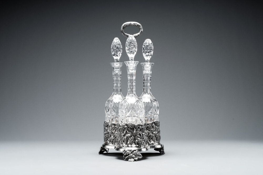 A sterling silver tantalus with three crystal-cut bottles and stoppers, 19/20th C.