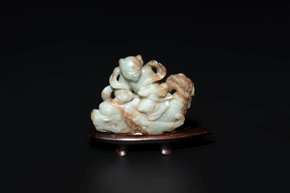 A Chinese celadon and russet jade figure of a boy riding a dragon carp, Qing