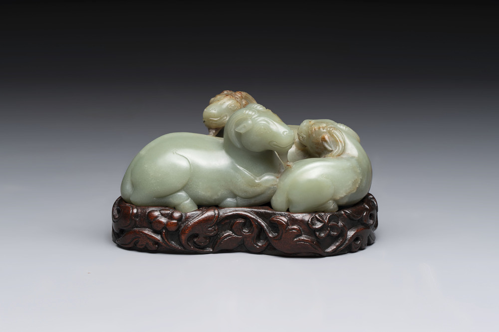 A Chinese celadon jade group of three goats on wooden stand, 19/20th C.
