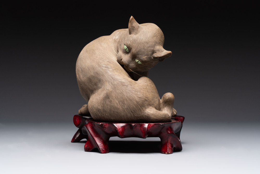 A Chinese Shiwan stoneware cat on a wooden stand, 20th C.