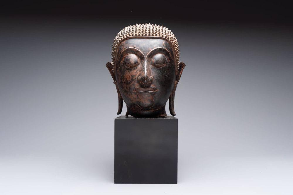 A large Thai bronze Shakyamuni Buddha head on wooden stand, Chieng Sen period, 16th C.