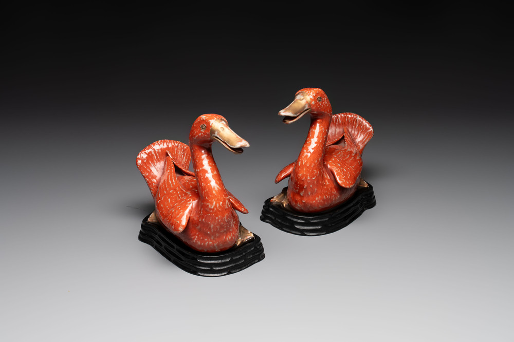 A pair of Chinese partly gilt coral-red-glazed models of ducks on wooden stands, 20th C.
